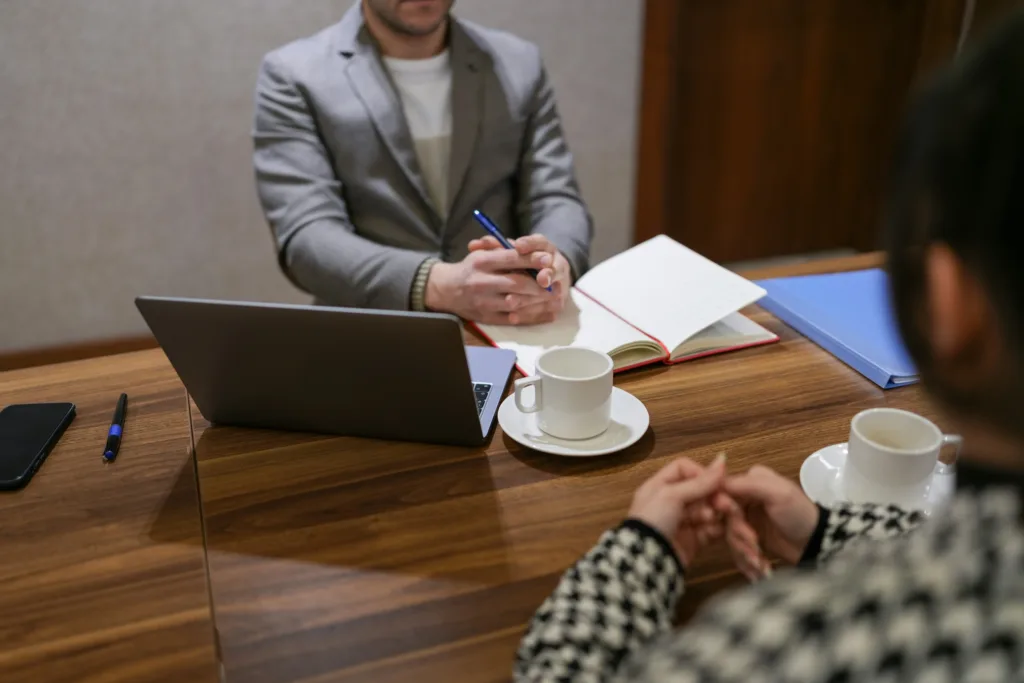 A man in a suit interviewing a woman at a table during a tech hiring.