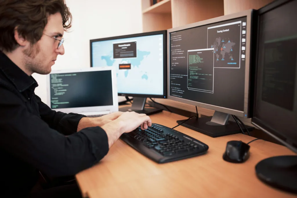 Man using the benefits of oop to code on four computer screens.