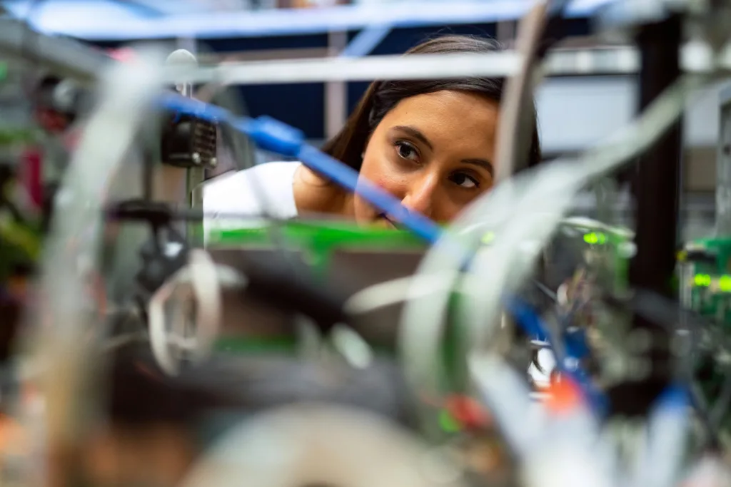 A woman peering through wires demonstrating What Is the Difference Between a Database Engineer vs Data Engineer?
