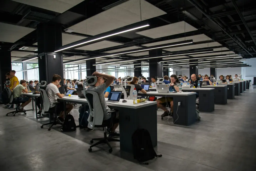 Large room with many people coding on computers.