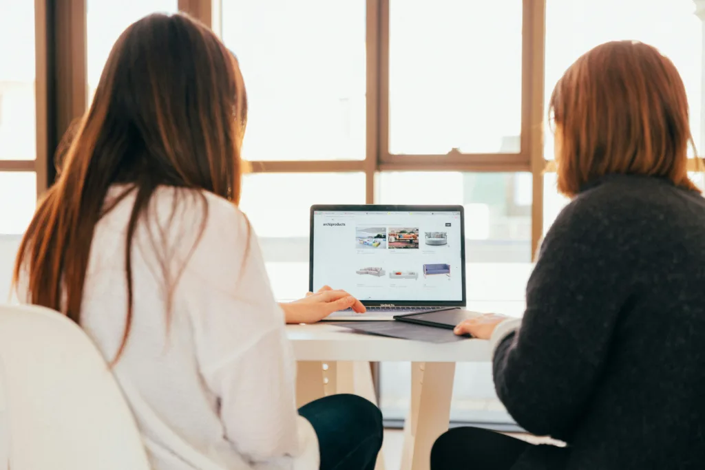 a tech assistant working with a client in front of a laptop showing their website design.
