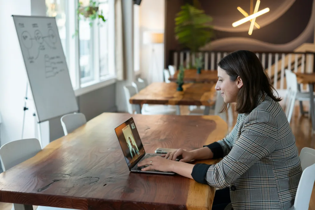 Woman working remotely on a laptop at a cafe showing the best Junior Developer Jobs For Techies.