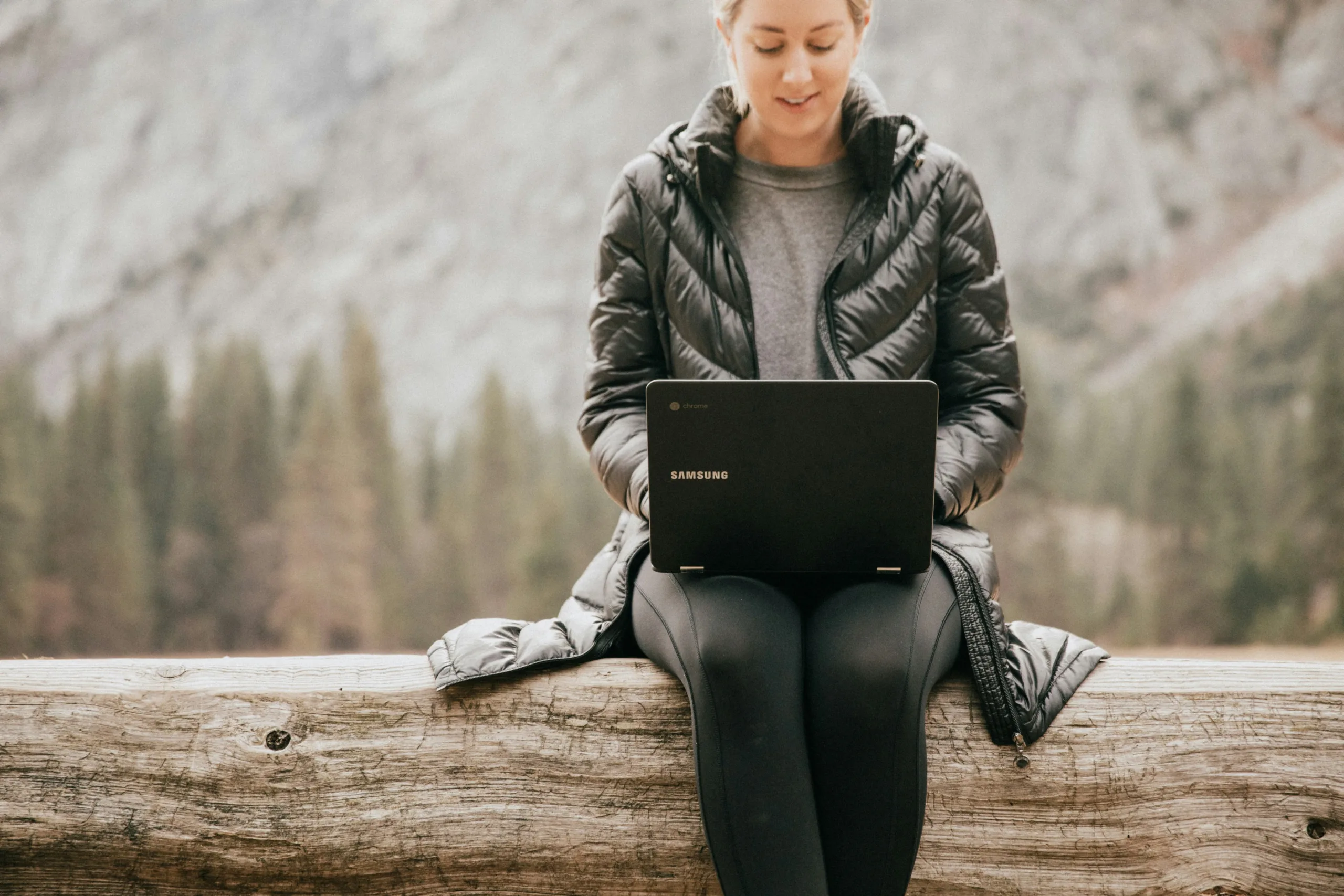 Woman working on a laptop in the woods showing the best junior developer jobs for techies.