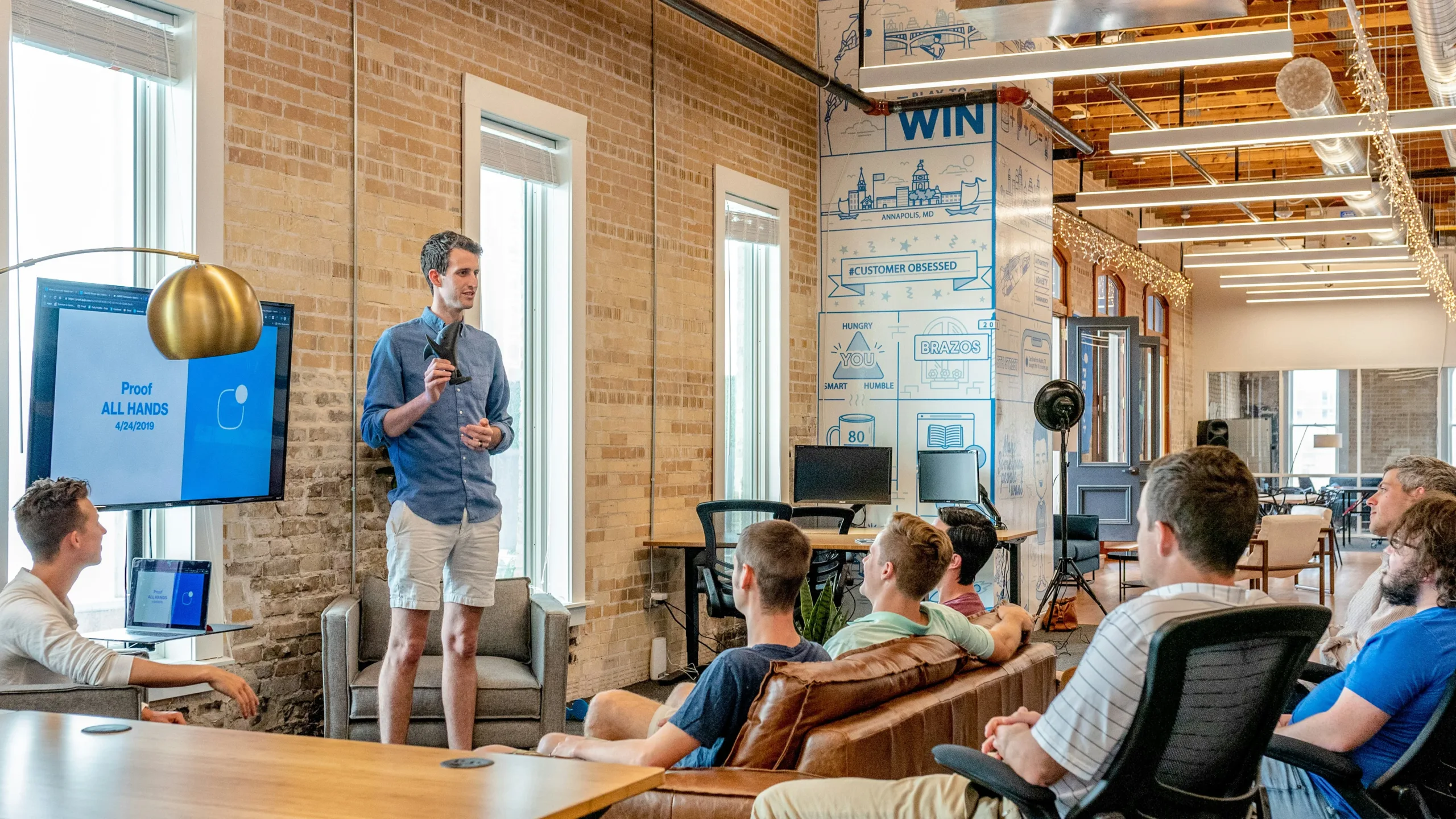 A man demonstrating his leadership by talking to a group of workers in an office.