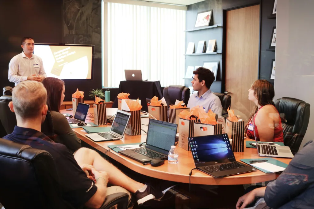 A group of workers having a leadership meeting around a oval wood table in a modern office.