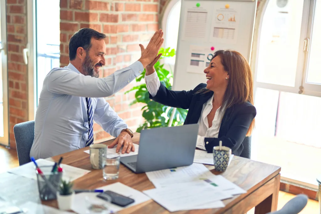 A man and woman high-fiving after working on their leadership development goals.