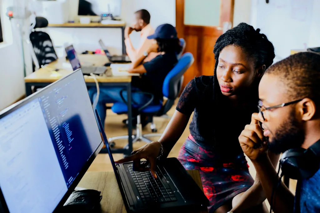A man and woman looking at a computer screen at a C# boot camp.