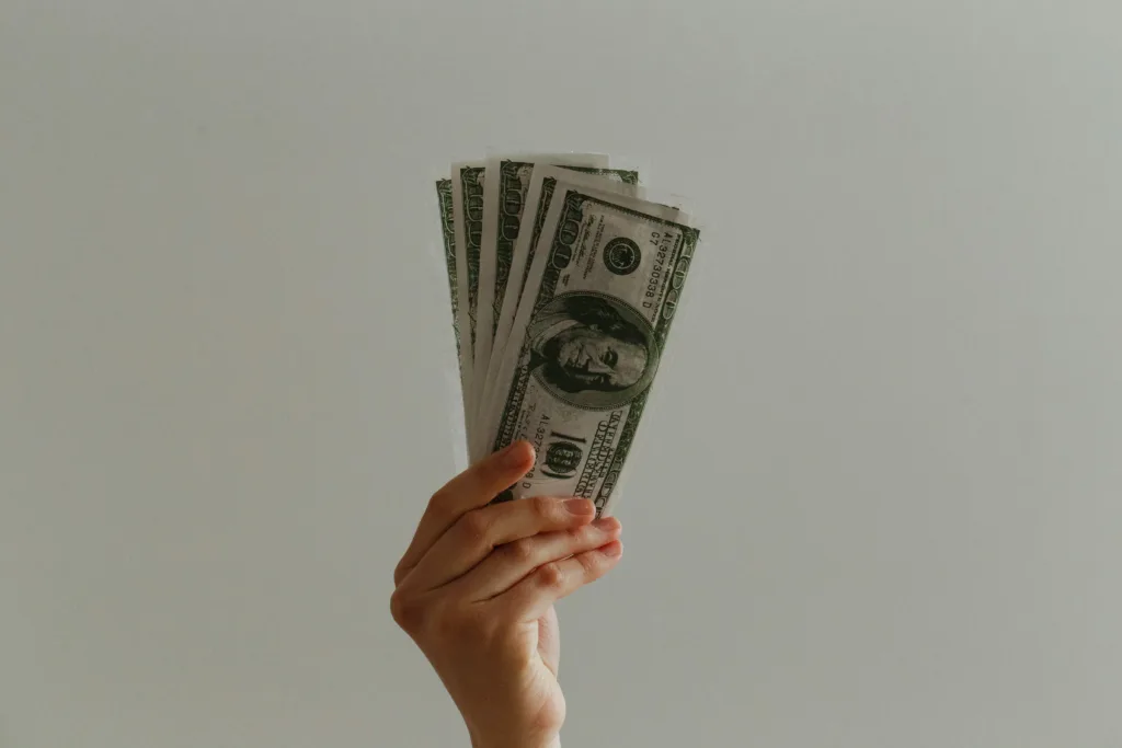 A hand holding cash against a white background.